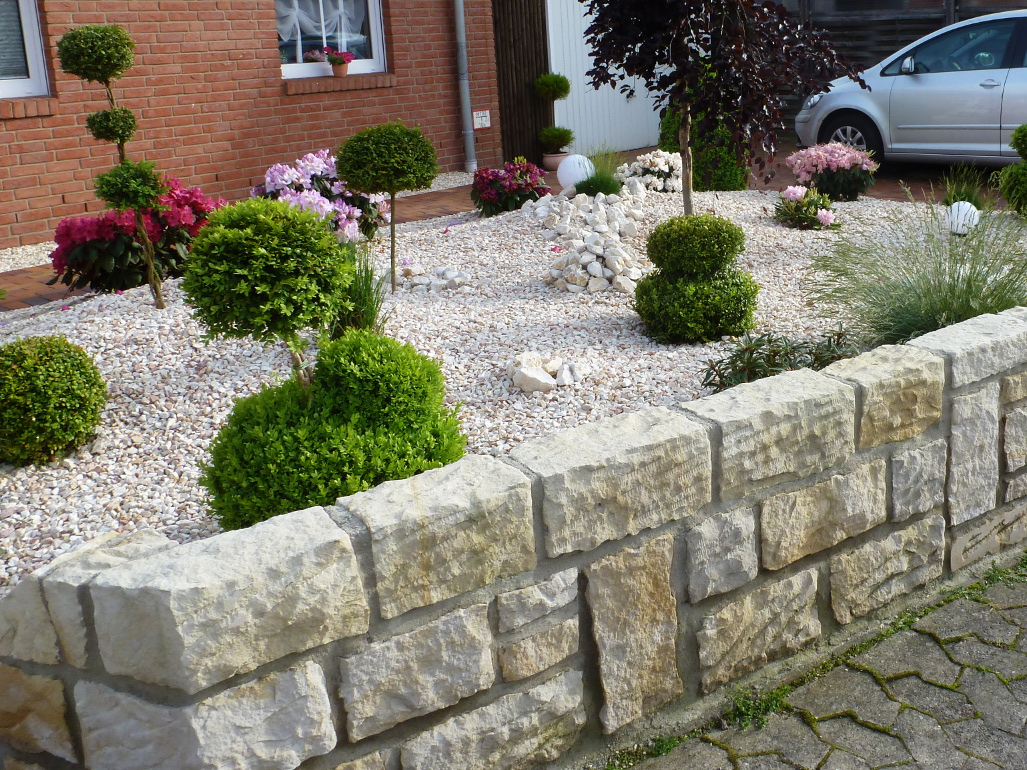 Vorgarten mit Kieselsteinen und weißer Mauer